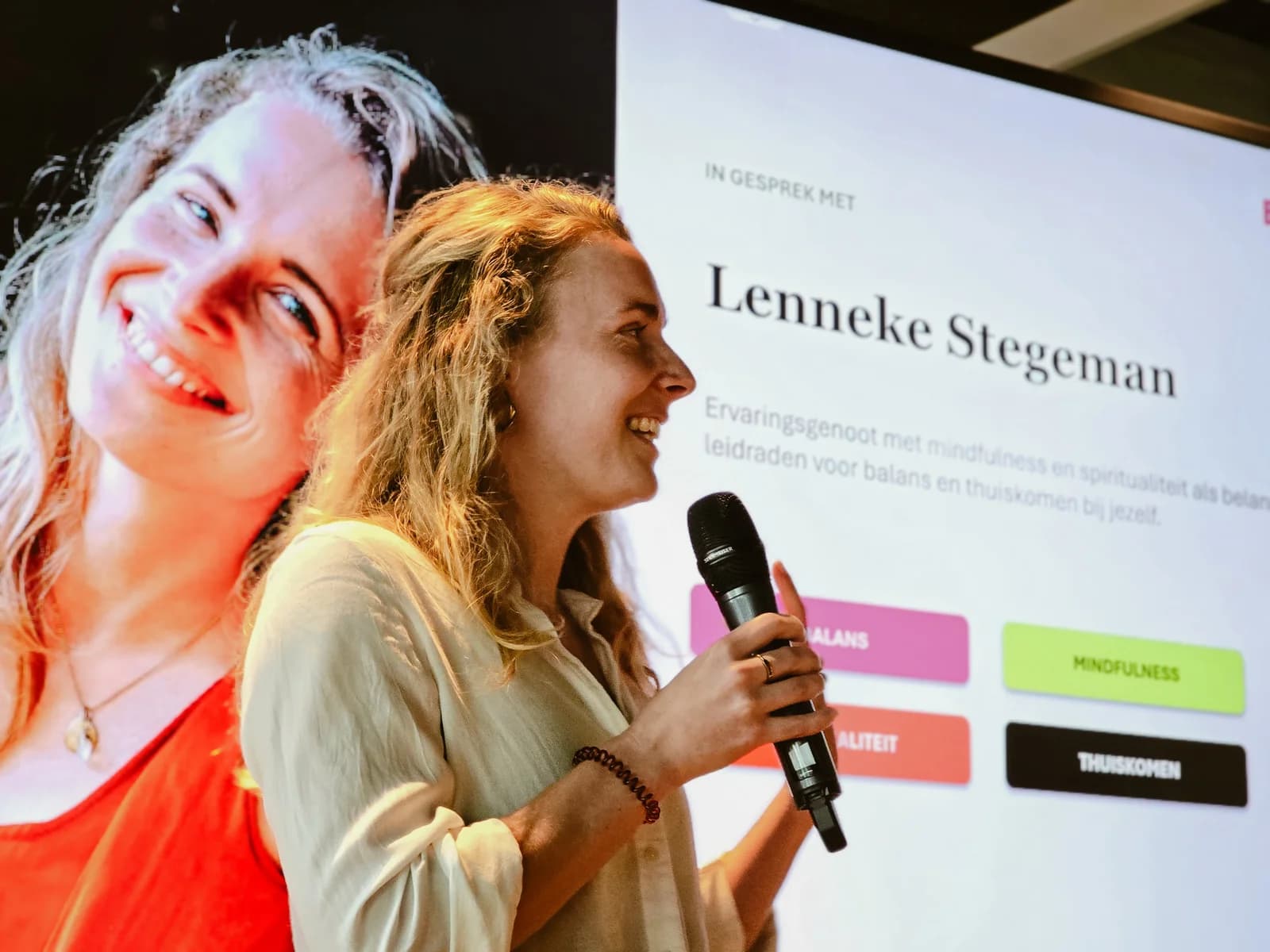 Lenneke spreekt met een microfoon voor een presentatiescherm